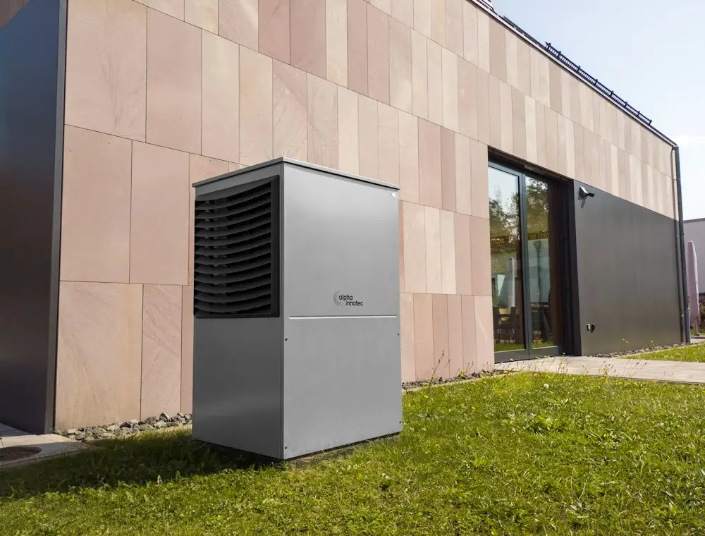 Wärmepumpe auf einer Rasenfläche vor einer Hausfassade