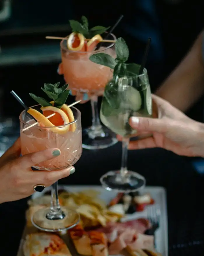 Drei Gäste stoßen mit Cocktails an