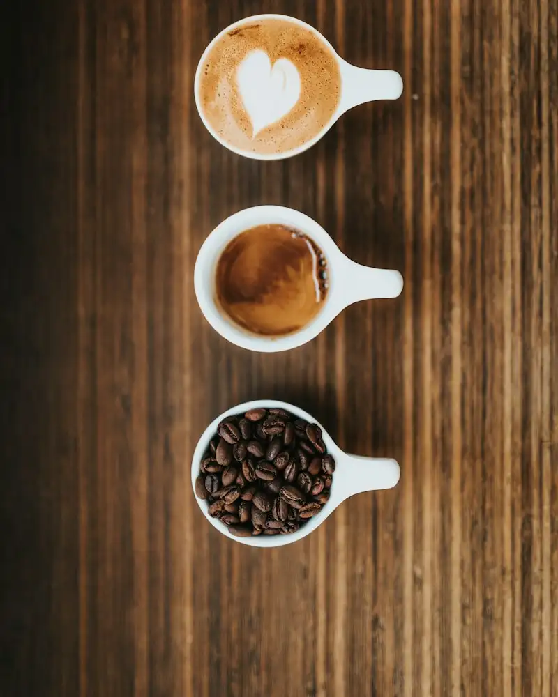 Drei Tassen mit Latte, Espresso und Bohnen von oben